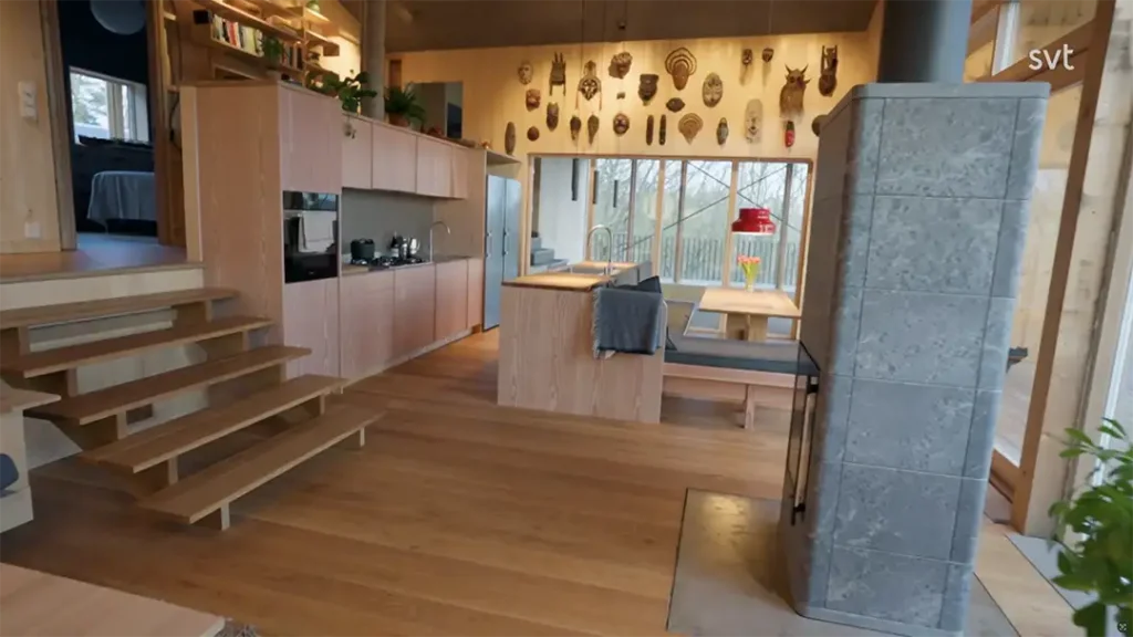 Stiligt - Ett modernt kök i Onsala - Husdrömmar stil med träskåp, öppna hyllor, en central ö och trätrappor; unika masker visas ovanför de stora fönstren.