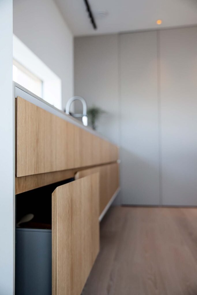 Stiligt - Modernt kök med stiligt design, ljusa träskåp, varav det ena är lätt öppet och en snygg metallblandare som syns i bakgrunden.