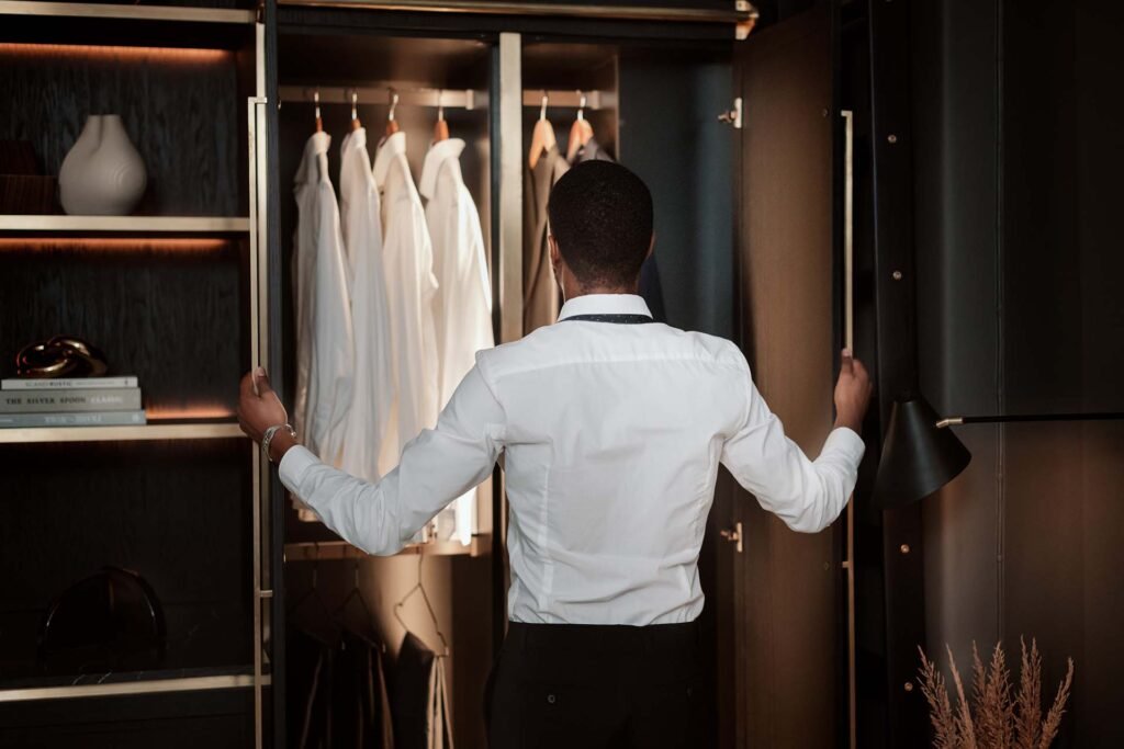 Stiligt - En person öppnar stilfullt en garderob och avslöjar en rad hängande vita skjortor inuti, sedda bakifrån.