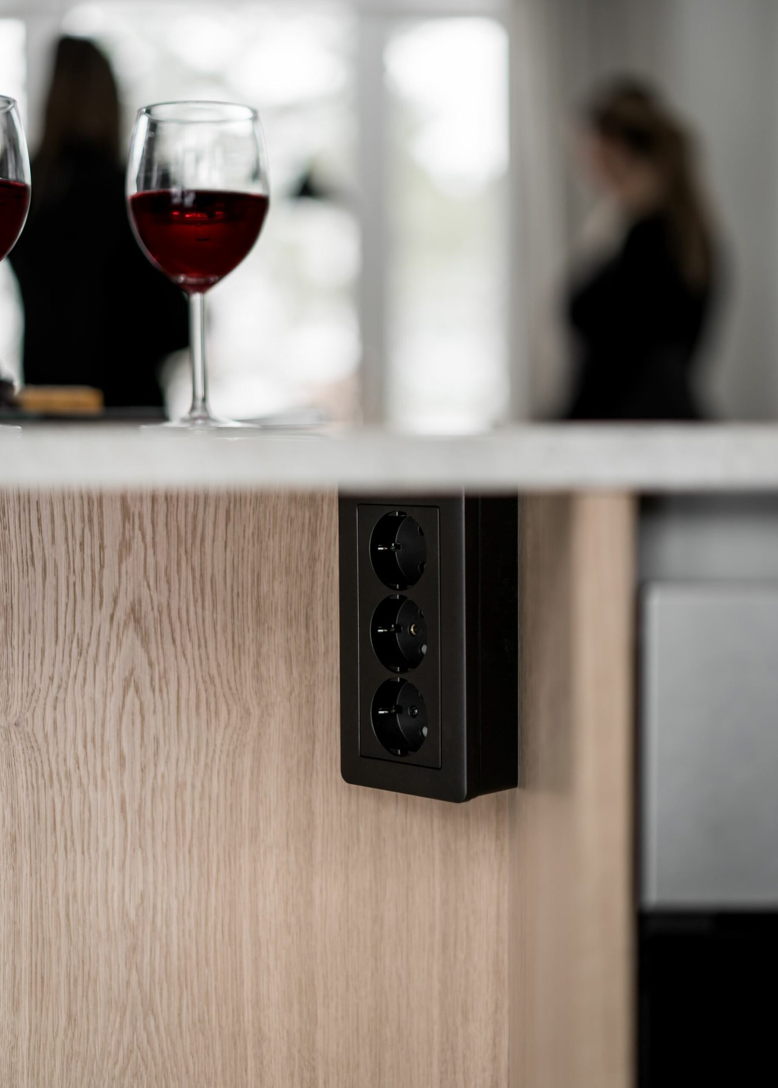 Stiligt - En stiligt trädisk rymmer två glas rött vin, accentuerat av en sidopanel med tre eluttag. Suddiga figurer hänger kvar i bakgrunden och ger en mystik atmosfär till den eleganta miljön.