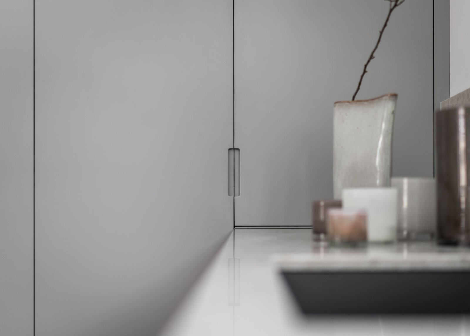 Stiligt - Stiligt minimalistisk inredning med en snygg skåpsdörr och en hylla med diverse ljus och en vas.