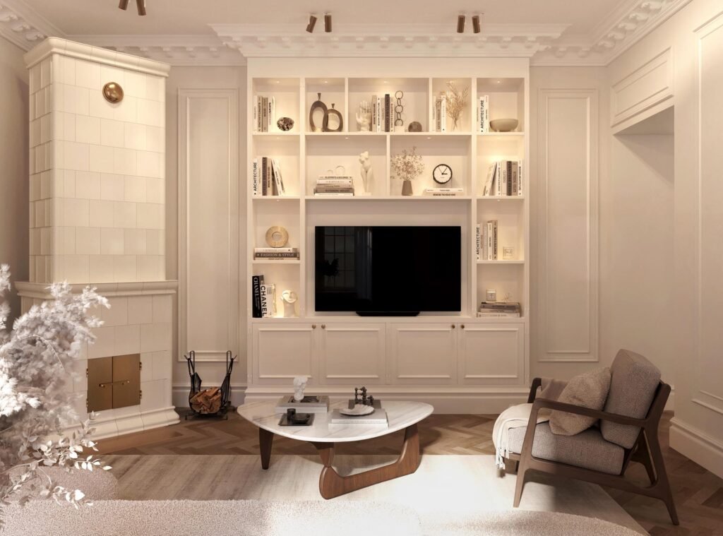 Stiligt - Ett modernt vardagsrum med platsbyggd bokhylla sekelskifte, platt-TV, neutrala möbler, ett soffbord i marmor och en vit kaklad öppen spis.