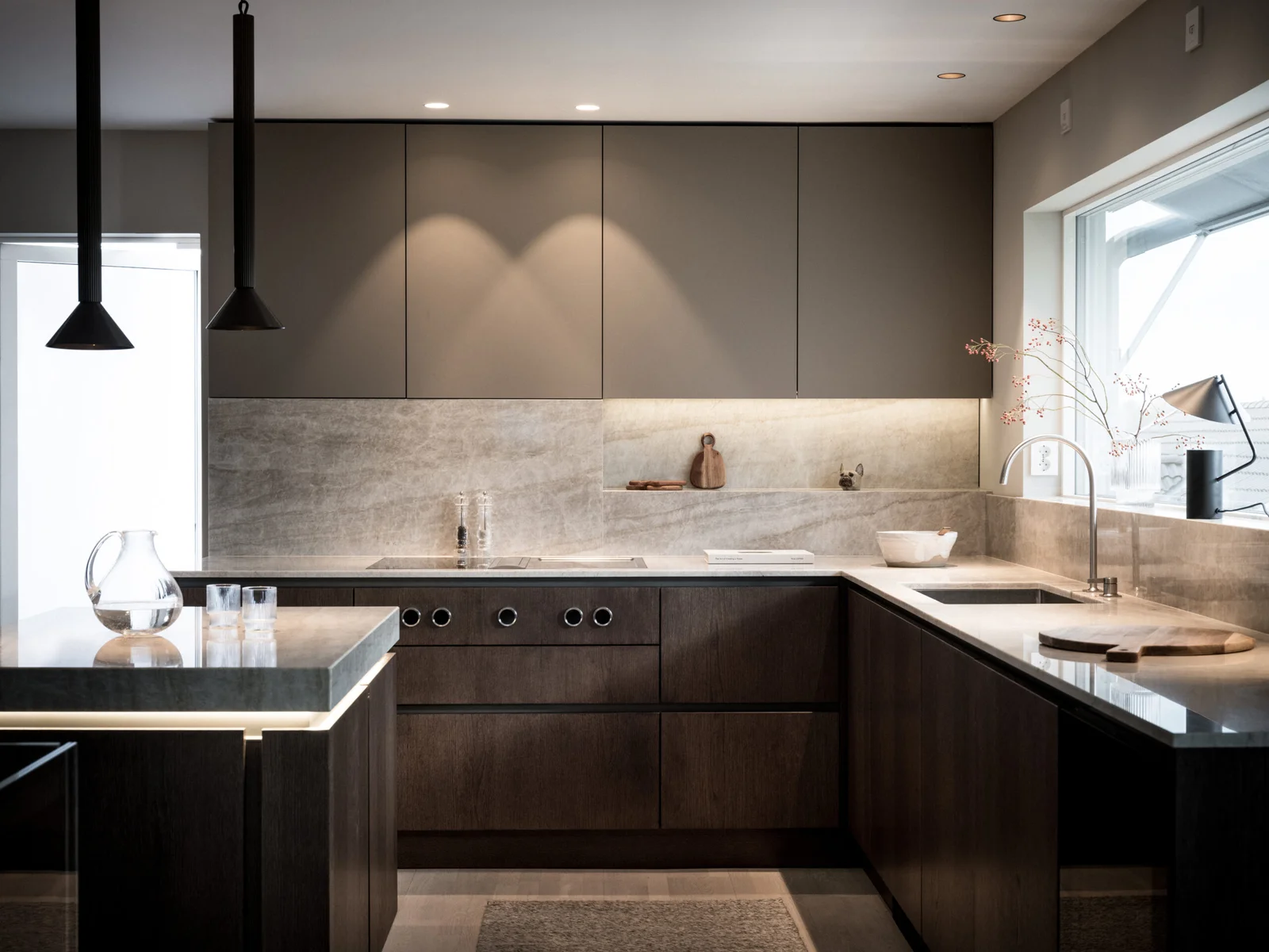 Stiligt - Modernt kök med skåp i mörkt trä, matta överskåp, inbyggda vitvaror och belysning under skåpen - med trenderna platsbyggda kök och minimalistisk bänkskivsinredning. Köksinspiration 2026 - de hetaste trenderna för platsbyggt kök: stil & funktion