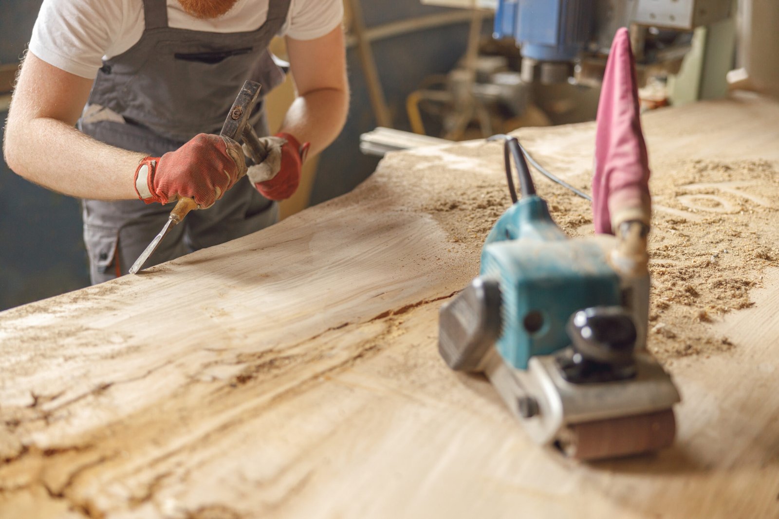 Stiligt: En snickare i tröja och förklädde står och jobbar med en stor slät träskiva. Fördjupning: Snickarens roll i skapandet av ett platsbyggt kök - expertens guide