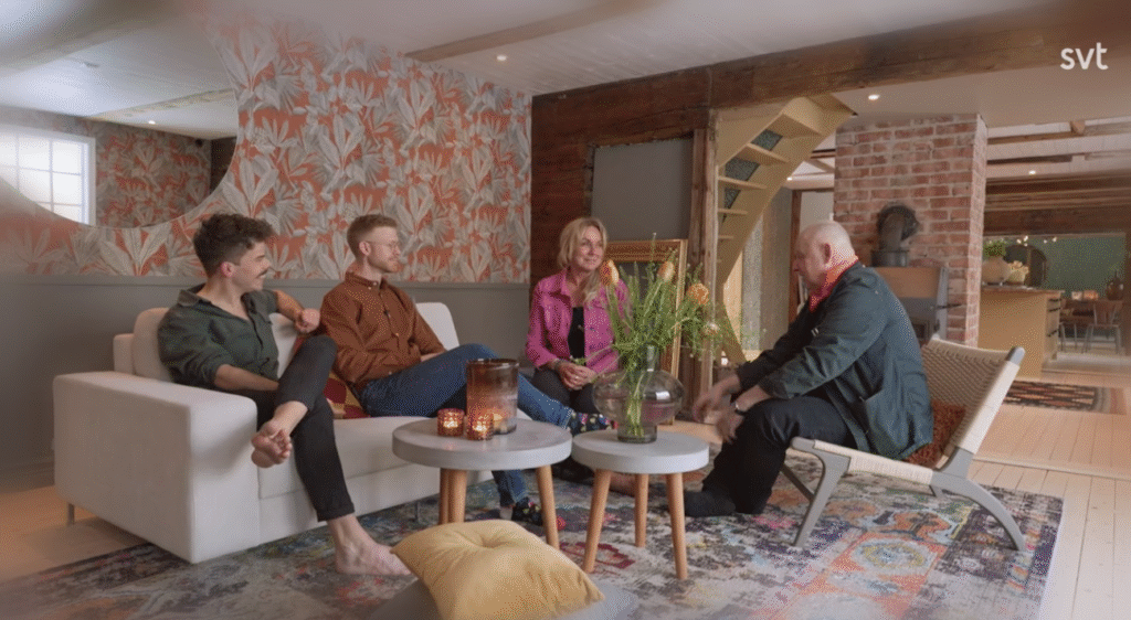 Stiligt - Fyra personer sitter och samtalar i ett modernt, varmt inrett vardagsrum med mönstrad tapet, levande ljus och olika växter.Säsong 13 Husdrömmar (2026) – Avsnitt för avsnitt