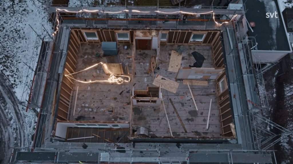 Stiligt - Flygfoto över en byggnad med borttaget tak och frilagda innerväggar, med skräp, byggmaterial och snö på marken utanför.