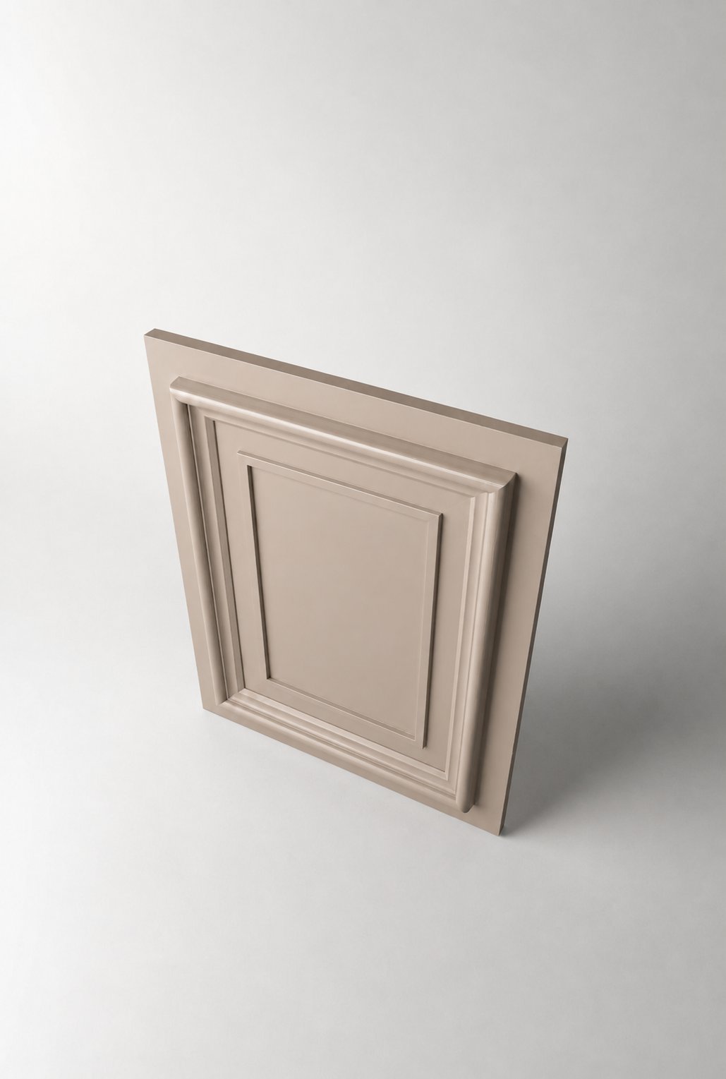 Stiligt - En enskild beige skåpdörr med upphöjda rektangulära paneler, fotograferad mot en enfärgad ljusgrå bakgrund från en vinkel ovanifrån.