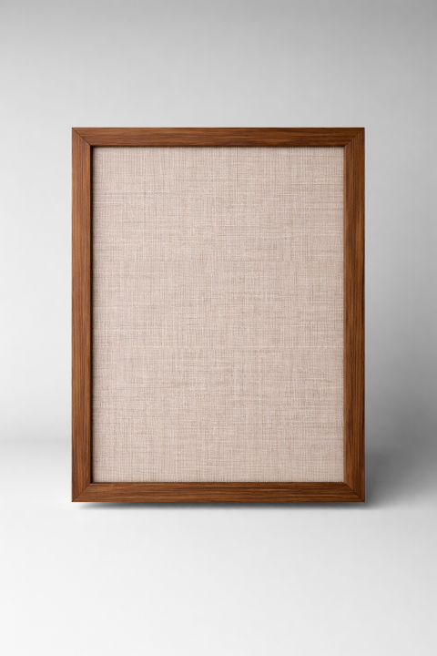 Stiligt - En tom tavelram i trä med ett beige texturerat tyg på insidan, som står upprätt mot en neutral grå bakgrund.