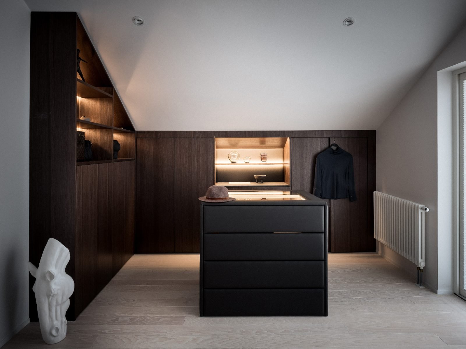 Stiligt - En modern, minimalistisk klädkammare med skåp i mörkt trä, upplysta hyllor, en central ö och en dekorativ vit skulptur på golvet – ett perfekt exempel på en skräddarsydd lösning för den stilmedvetna.