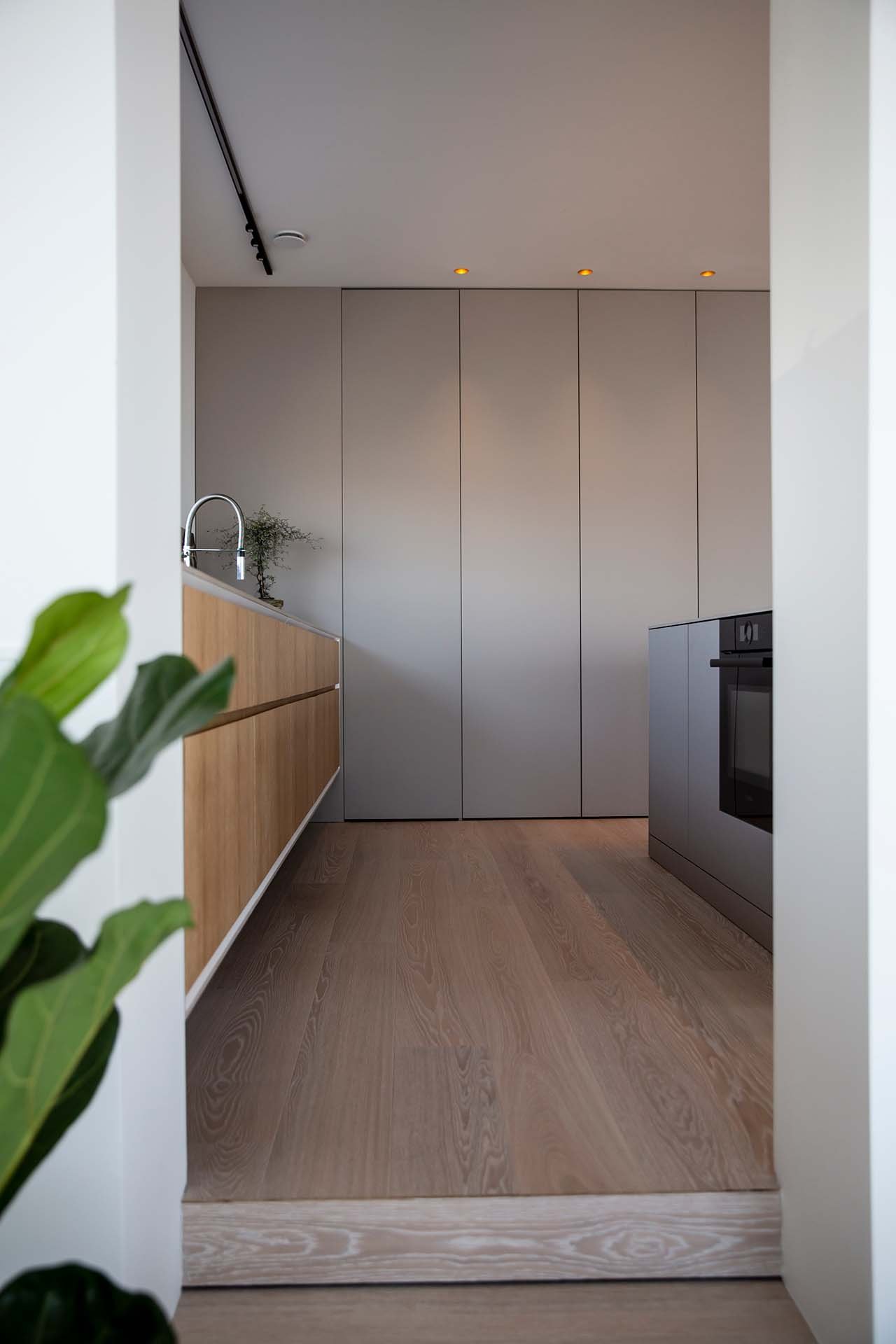 Hoga-luckor-golv-till-tak-minimalistiskt-kok-Arizona-beige-Tarkett-ekparkett-bosch-ugn-supermodular-belysning-platsbyggt-kok.jpg