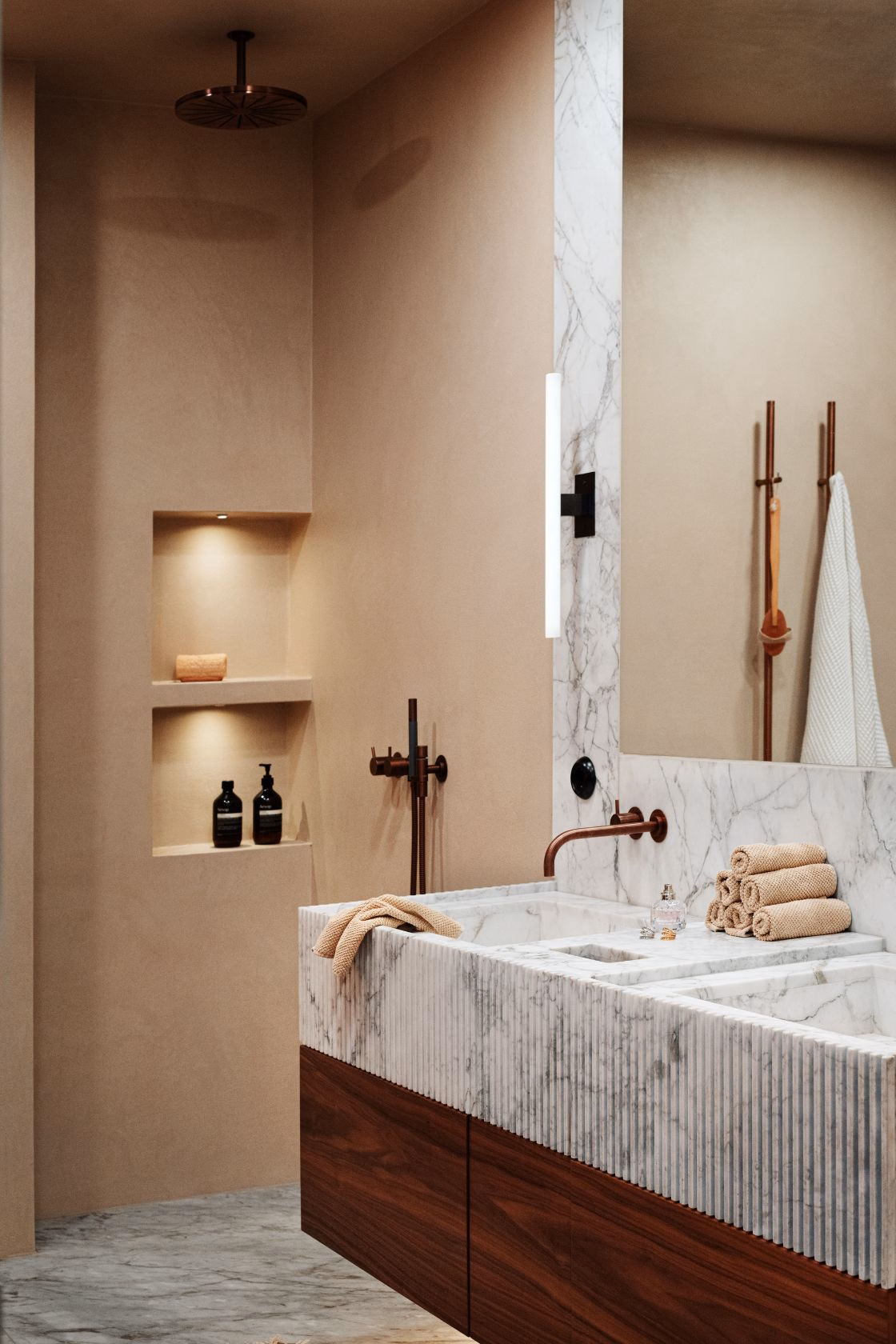 Stiligt - Modernt badrum med handfat i marmor, inslag av trä, en väggnisch för toalettartiklar, handdukshängare och en stor spegel; en neutral färgskala i beige och vitt.